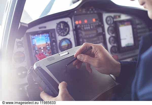 Airplane pilot using stylus on digital tablet in cockpit