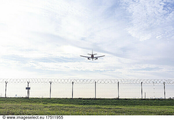 Airplane preparing to land over wire fence