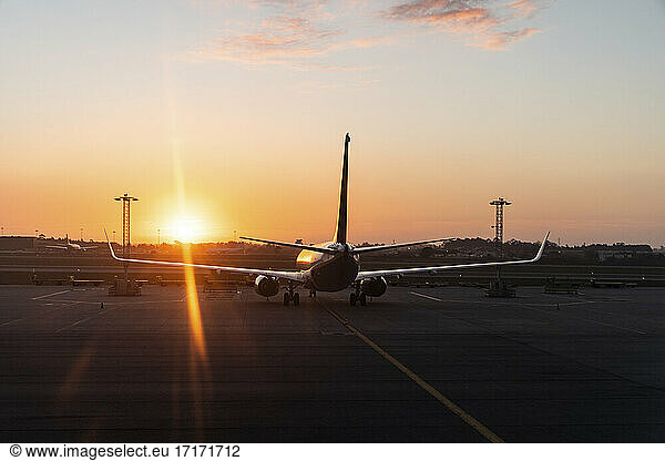 Airplane standing in airport at sunset