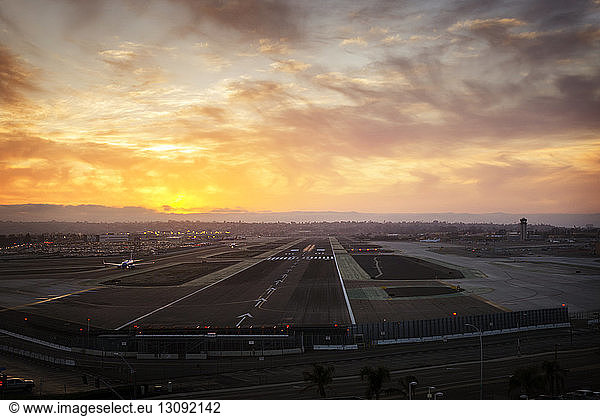 Airport runway against cloudy sky during sunset