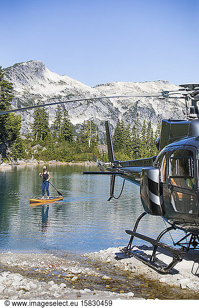 Aktive Frau paddelt auf einem abgelegenen See  zu dem ein Hubschrauber Zugang hat.