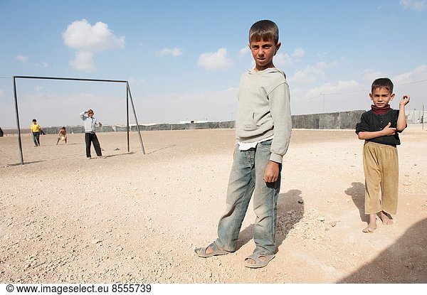 Al Za'atari  Al Za'atari  Al Mafraq  Jordan. Five Syrian refugee boys playing on UNHCR refugee camp child safe place football or soccer field in the middle of the Jordanian dessert.