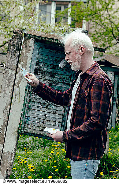 Albino man checking his letters near the blue mailbox