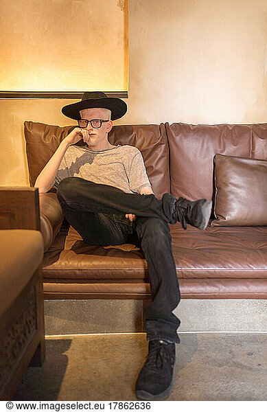Albino man portrait sitting on the leather couch looking at the camera