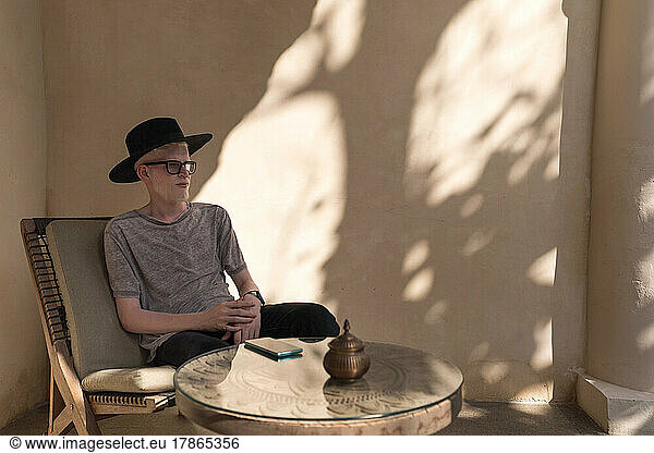 Albino man sitting at the outdoor cafe looking away