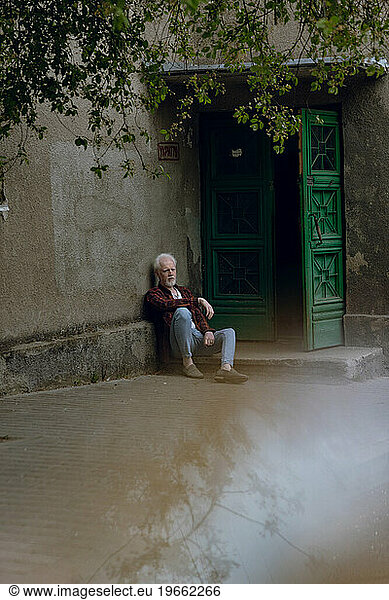 Albino man sitting on the steps at the entrance to the house