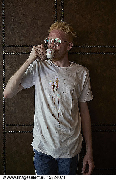 Albinomann mit weißem  mit Kaffeetropfen beflecktem T-Shirt