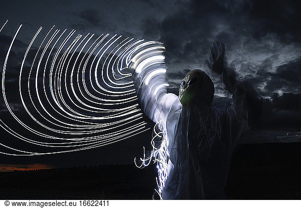 Alien standing by semi-circle light trails against sky at night
