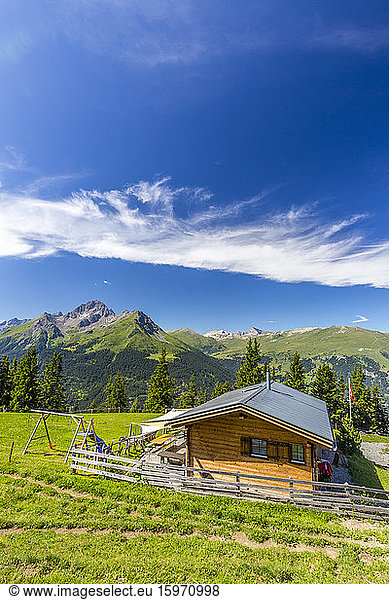 Alpine hut with Swiss flag  beneath stunning clouds. Surses  Surselva  Graubunden  Switzerland  Europe