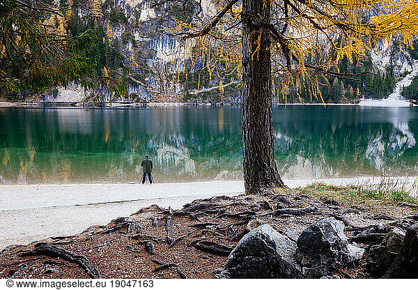 Alpine mountain lake at autumn morning with unrecognizable photographer making picture