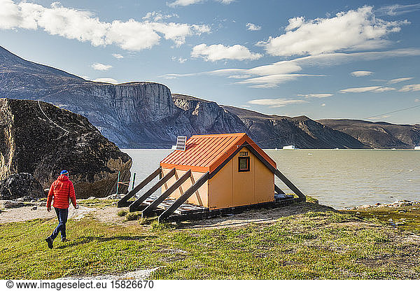 Alpinist approaches emergency shelter at North Pangnirtung Fiord