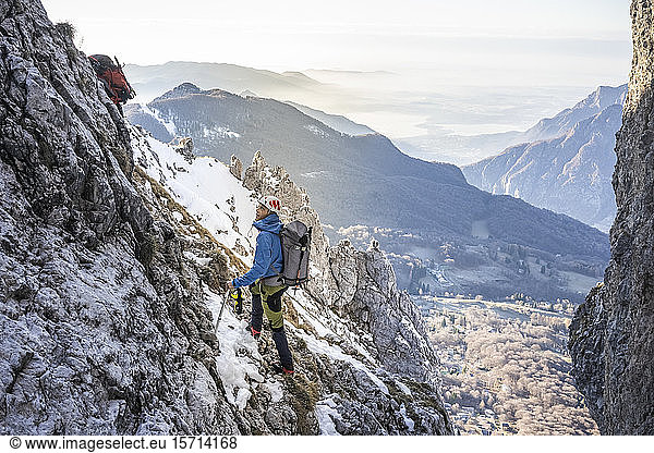Alpinist standing in a rocky snowy mountain looking up  Orobie Alps  Lecco  Italy