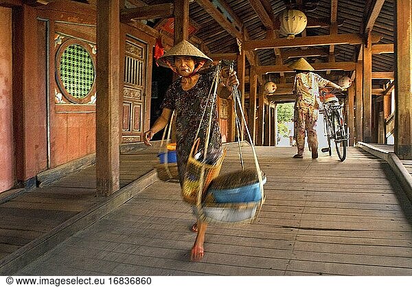 Alte Frau auf einem Fahrrad überquert die japanische überdachte Brücke in Hoi An  UNESCO-Weltkulturerbe  Vietnam  Indochina  Südostasien  Asien.
