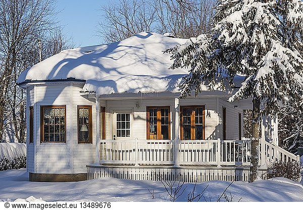 Alte  mit weißen Holzplanken verkleidete Hausfassade mit braunen Zierleisten und blauem Blechdach im Winter  Quebec  Kanada  Nordamerika
