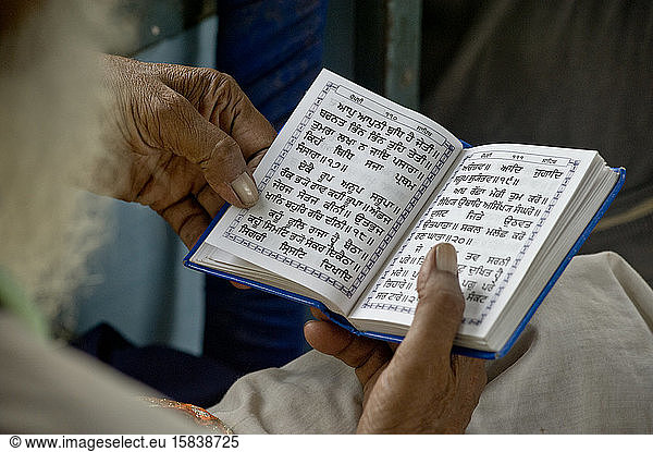 Alter Sikh-Mann liest religiöses Buch im Zug