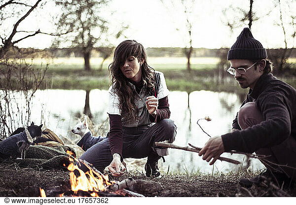 alternative friends gather around fire with dogs roasting marshmallows