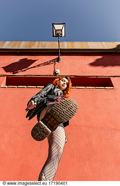 Alternative girl with orange hair stepping on the camera with her boot.