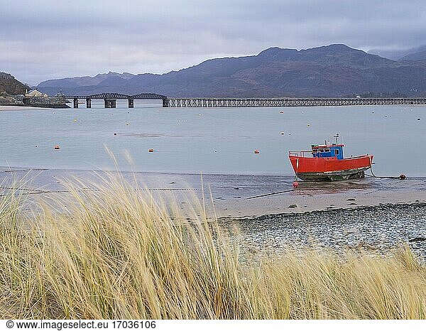Altes Fischerboot und Barmouth Bridge im Hafen von Barmouth mit dem Cader (Cadair) Gebirge im Hintergrund (Teil des Snowdonia National Park)  Gwynedd  Nordwales  Wales  Vereinigtes Königreich  Europa