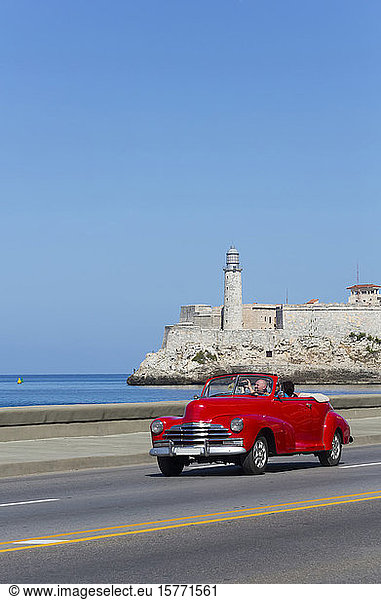 Altes klassisches rotes Cabrio auf dem Malecon  Castillo del Morro (Hintergrund); Havanna  Kuba
