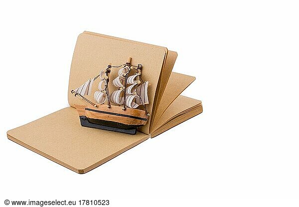 Altes Schiff auf einem Notizbuch auf weißem Hintergrund