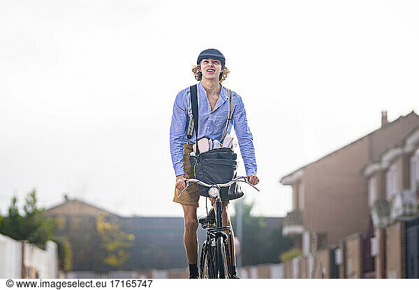 Altmodischer Zeitungsjunge steht beim Radfahren gegen den Himmel