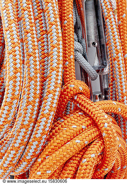 Am Mast einer Yacht befestigte orangefarbene Seile zum Segeln