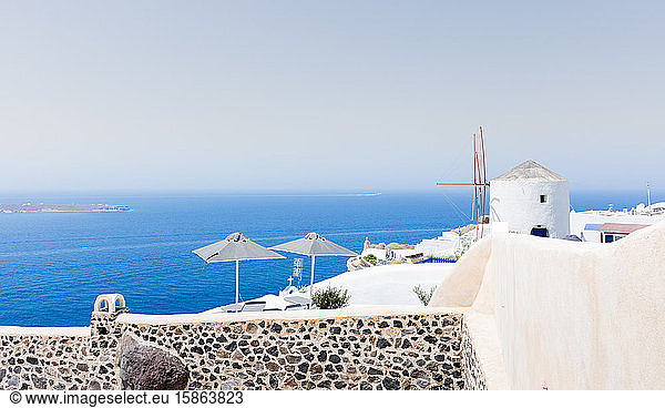 amazing panoramic view of some white houses of the village of touristic Oia in Santorini island in Aegean sea. The windmill is at the top of the village and the sea at the background. Horizon