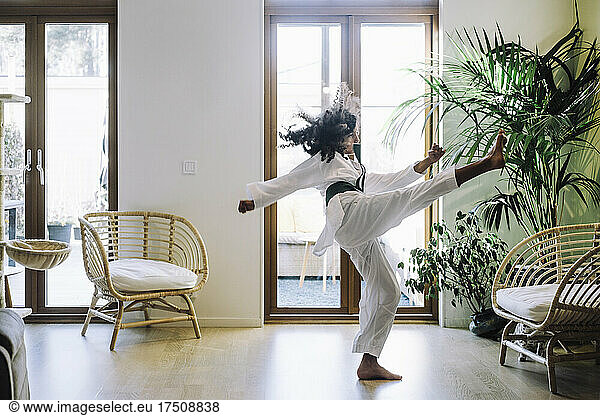 Ambitious girl practicing karate in living room
