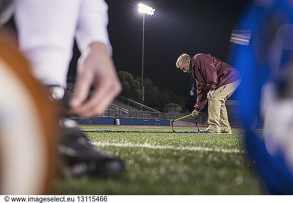 American-Football-Trainer stellt Agility-Leiter auf Rasen im Stadion auf