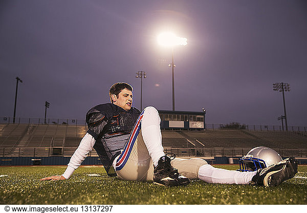 American-Footballer entspannt sich auf Rasenplatz im Stadion gegen den Himmel