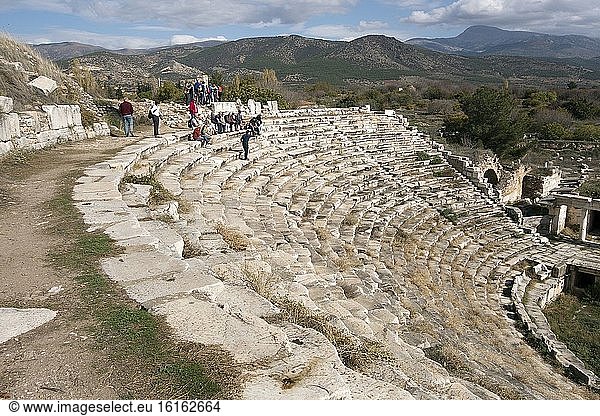 Amphitheater von Aphrodisias. Der untere Teil des Zuschauerraums ist intakt,  mit neun Reihen von Marmorsitzen,  die in fünf Keile mit radialen Treppen unterteilt sind. Die Sitze im oberen Teil,  die weitere zwölf Reihen umfassen,  sind zusammen mit den Stützbögen eingestürzt. Ruinen in der antiken Stadt Aphrodisias. Türkei. Die Überreste des antiken Aphrodisias lagen teilweise unter dem Dorf Geyre mit etwa 950 Einwohnern verborgen. Die Ausgrabungen begannen in den frühen 1960er Jahren. Das Dorf Geyre wurde bei Beginn der Ausgrabungen verlegt. Foto: Andr? Maslennikov