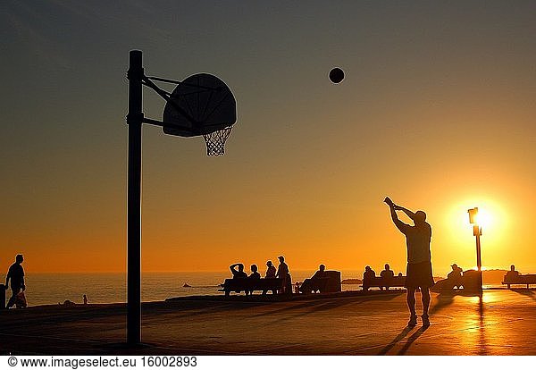 An adult man takes a shot at a seaside basketball court near Laguna Beach  California.