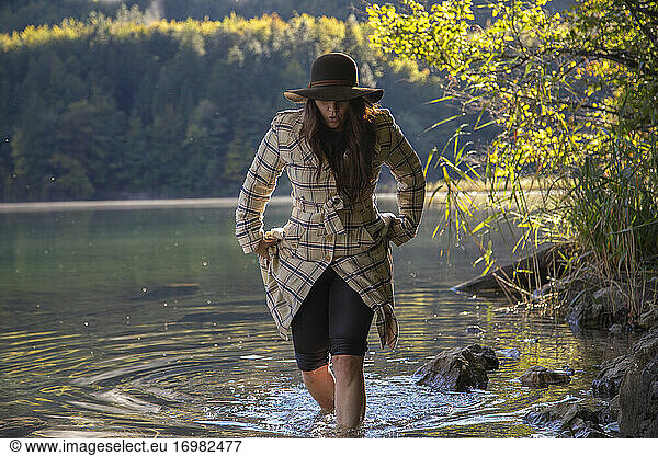 An adventurous woman wades along the shallows of a chilly alpine lake