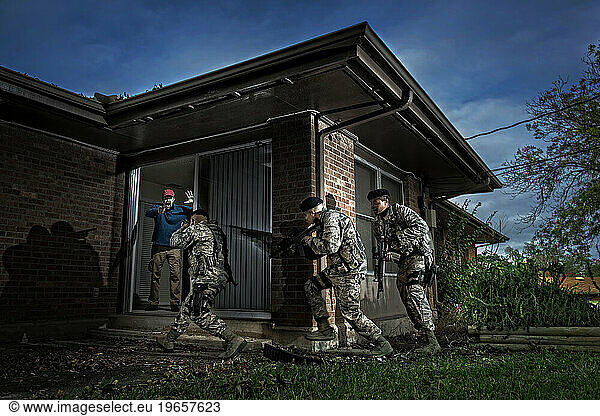 An Air Force Security Forces team prepare to take down an armed perpetrator inside a domestic home during a simulated hostage situation.
