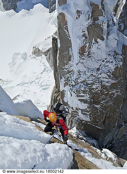 An alpinist climbs past snow and ice on the steep north face of Cerro Torre.