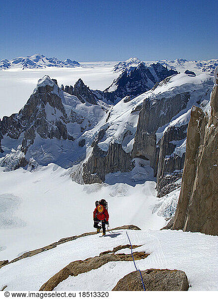 An alpinist climbs the steep northwest face of Cerro Torre  with the peaks of Cerro Rincon and the glaciers of the SouthernPata