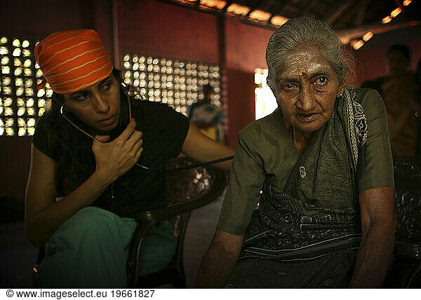 An American doctor listens to an elderly Sri Lankan woman breathe at a clinic  one year after the tsunami  Kalmunai  Sri Lanka.