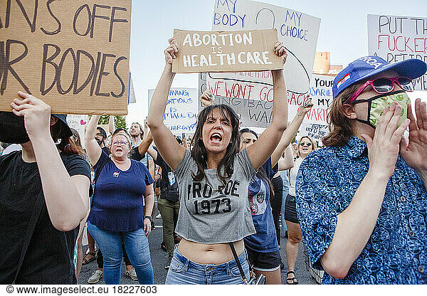 An angry woman stands in crowd holding pro-choice sign at rally