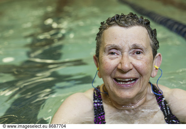 An elderly woman in a swimming pool  taking exercise.
