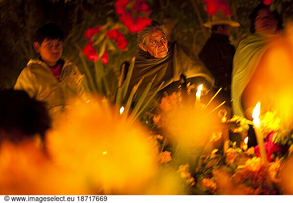 An elderly woman is surrounded by flowers in the Atzompa cemetery during 'Dia de los Muertos' or Day of the Dead festivities in Oaxaca  Mexico.