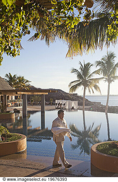 An employee carries towels next to a pool scene at a luxury hotel in La Paz  Mexico.