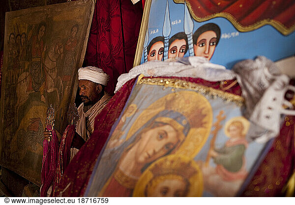 An Ethiopian Orthodox priest stands amidst ancient religious paintings in Bet Giyorgis  Lalibela  Northern Ethiopia.