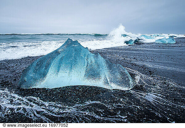 An iceberg chunk on black sand Diamond Beach in Iceland during winter