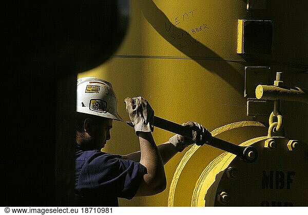 An oil-drilling worker does maintenance on machinery.