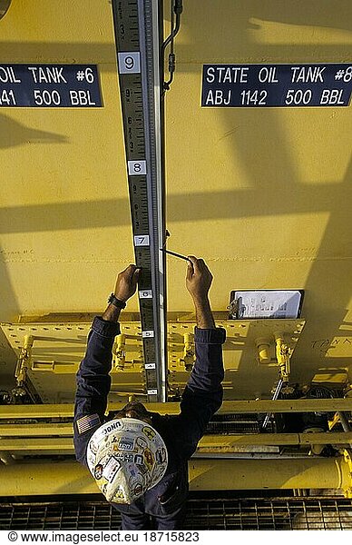 An oil-drilling worker does maintenance on machinery.