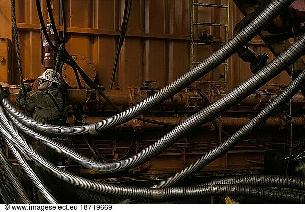 An oil rig worker fixes pipes.