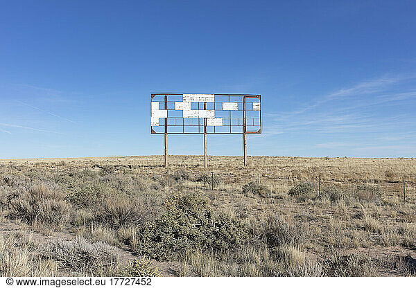 An old billboard  empty panels  in the middle of desert scrub.