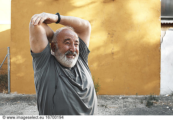 An old man is stretching out his arm with a sore face