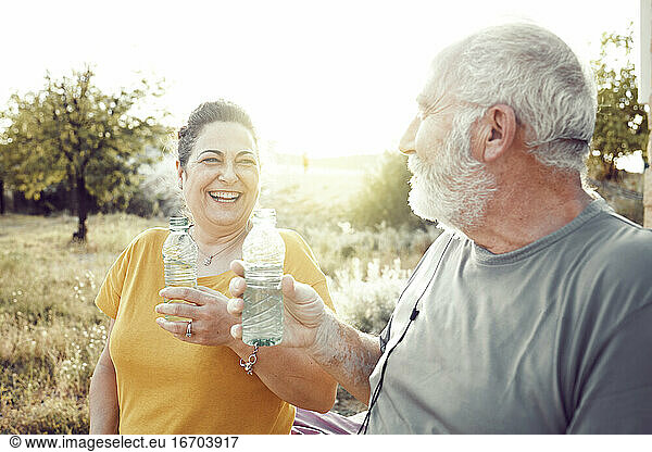 An older couple laughs while resting to drink water