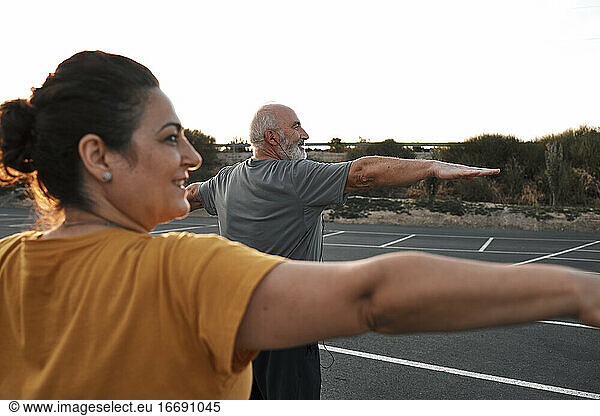 An older couple practices yoga outdoors.